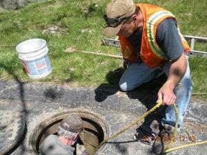 Photo of man's head as he goes down sewer- manhole cover removed